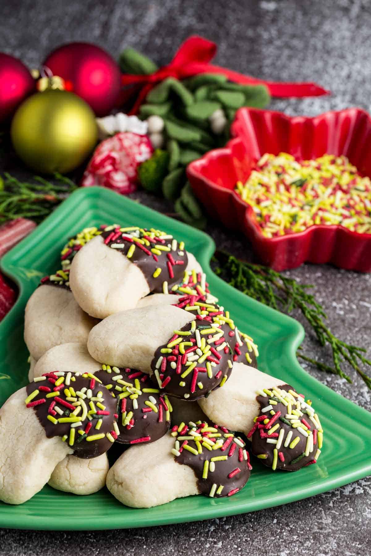 Make tender, buttery gluten-free almond crescent cookies dipped in chocolate! They're the easiest Christmas cookies with only 4 ingredients. Chocolate-dipped almond crescents stacked on a Christmas tree platter.