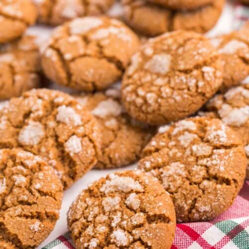 Ginger snap cookies scattered on a red and green plaid napkin.