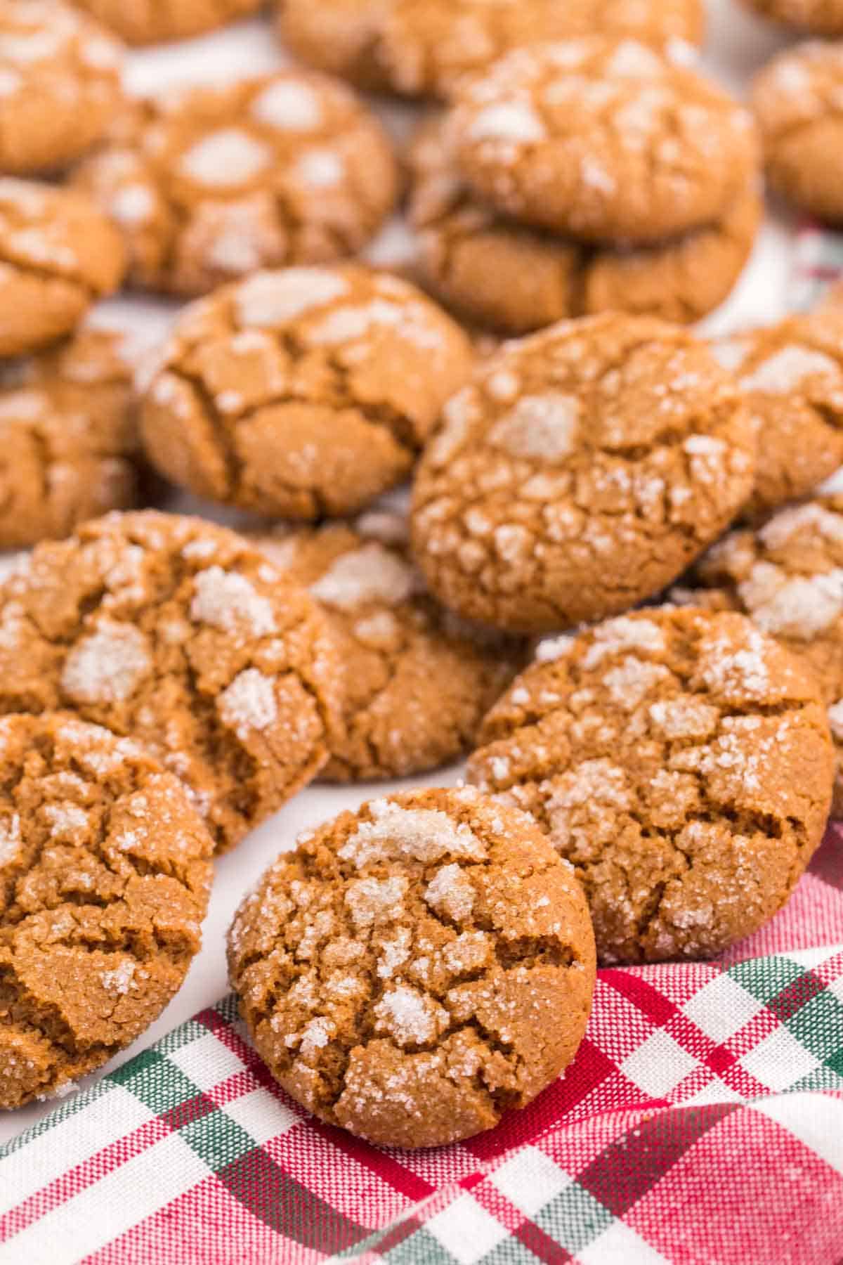 Ginger snap cookies scattered on a red and green plaid napkin.