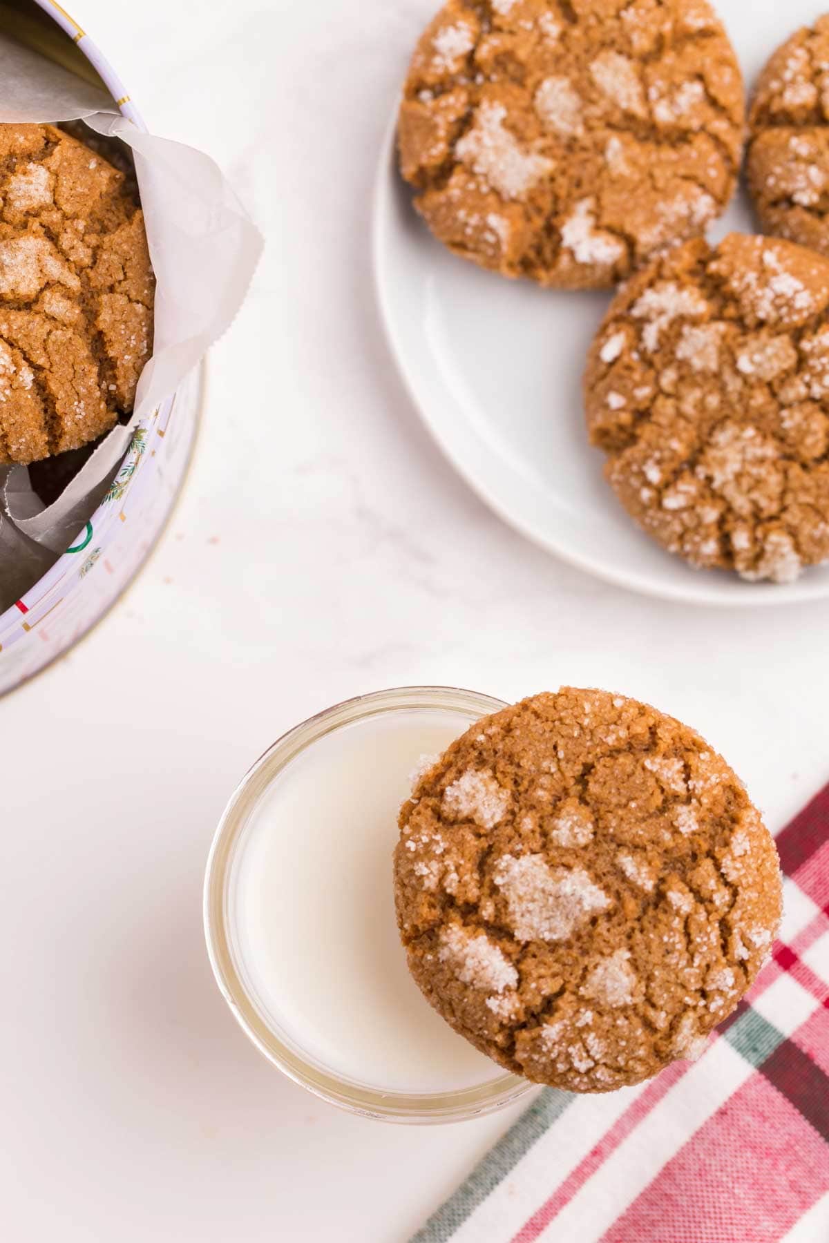 A ginger snap cookie resting on top of a glass of milk.