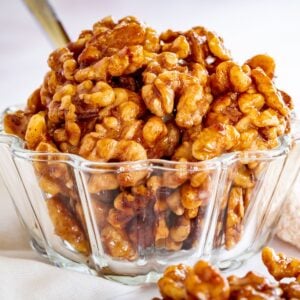 A glass bowl of honey glazed walnuts.