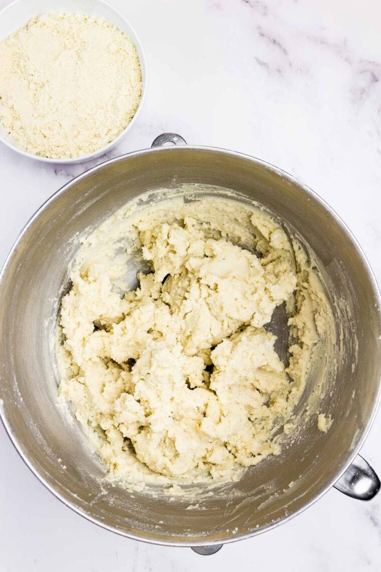 Cookie dough in a bowl with a bowl of almond flour next to it to be mixed in.