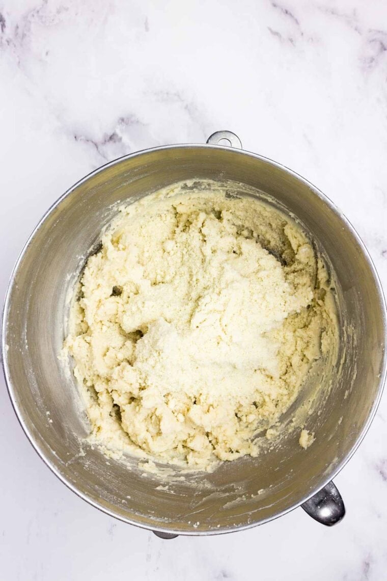 Almond flour on top of the partially made cookie dough in a metal bowl.