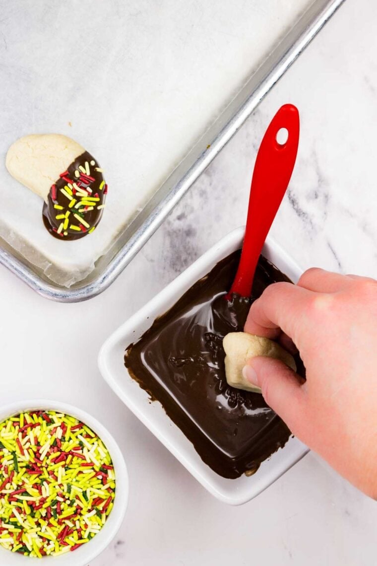 A cookie being dipped in melted chocolate.
