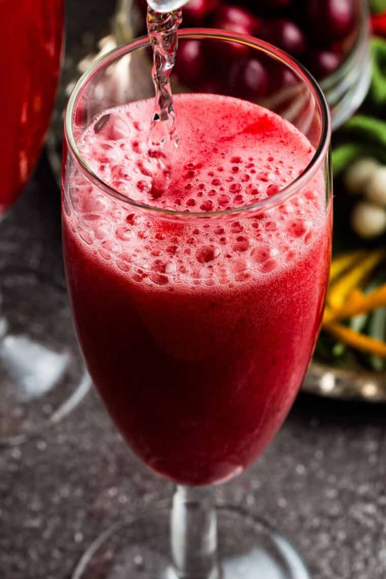 Seltzer being poured into the flute glass with the cranberry juice.