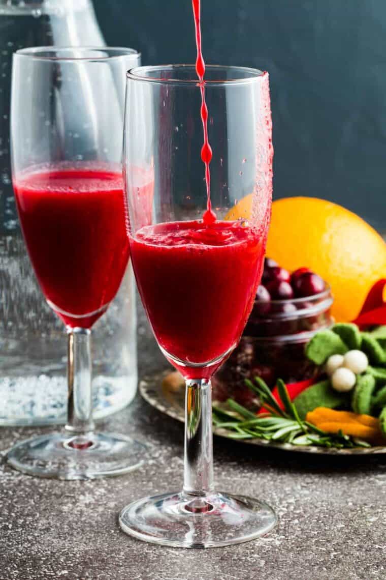 Fresh cranberry juice being poured into a flute glass.