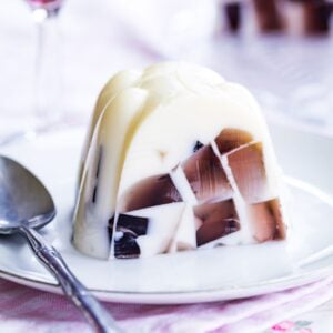 A slice of ice cream float jello mold with purple gelatin cubes on a plate with a spoon.