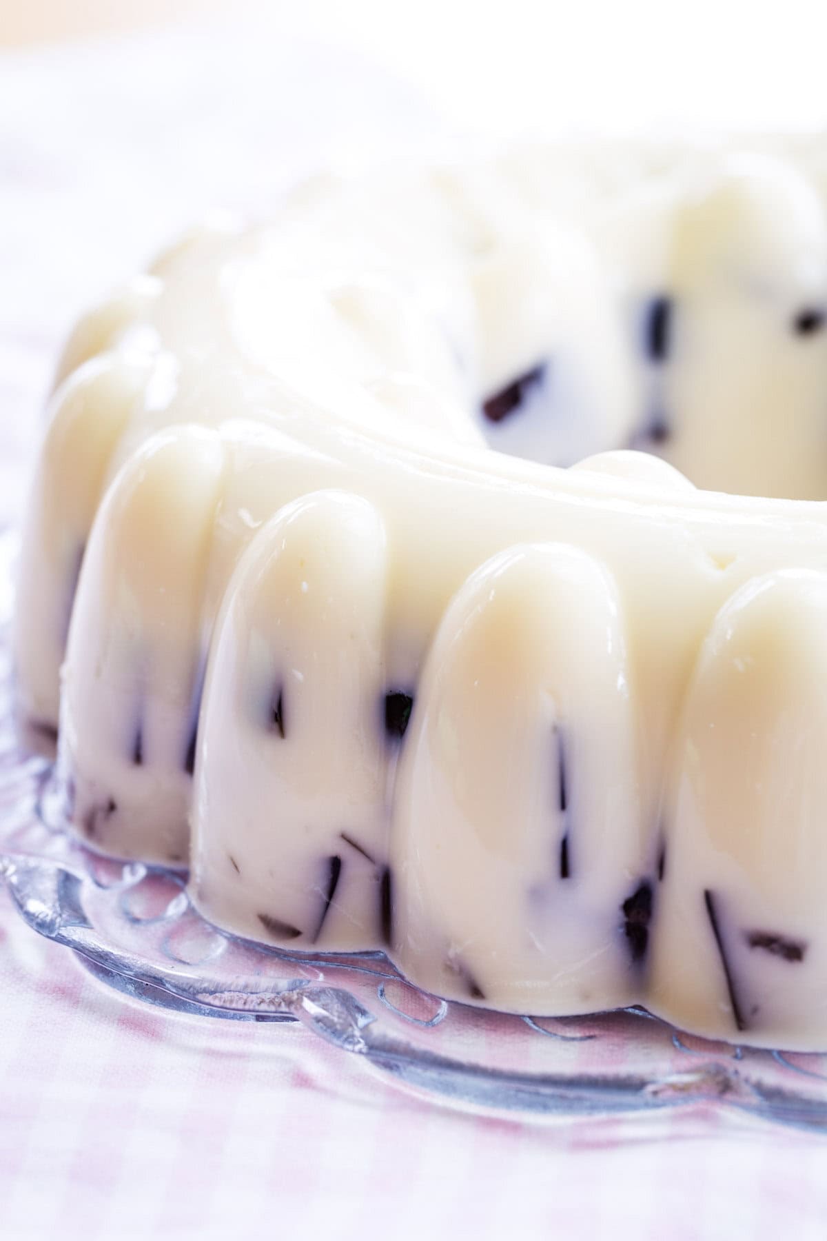 A vanilla ice cream jello mold with some of the purple gelatin cubes visible on the side on a platter.