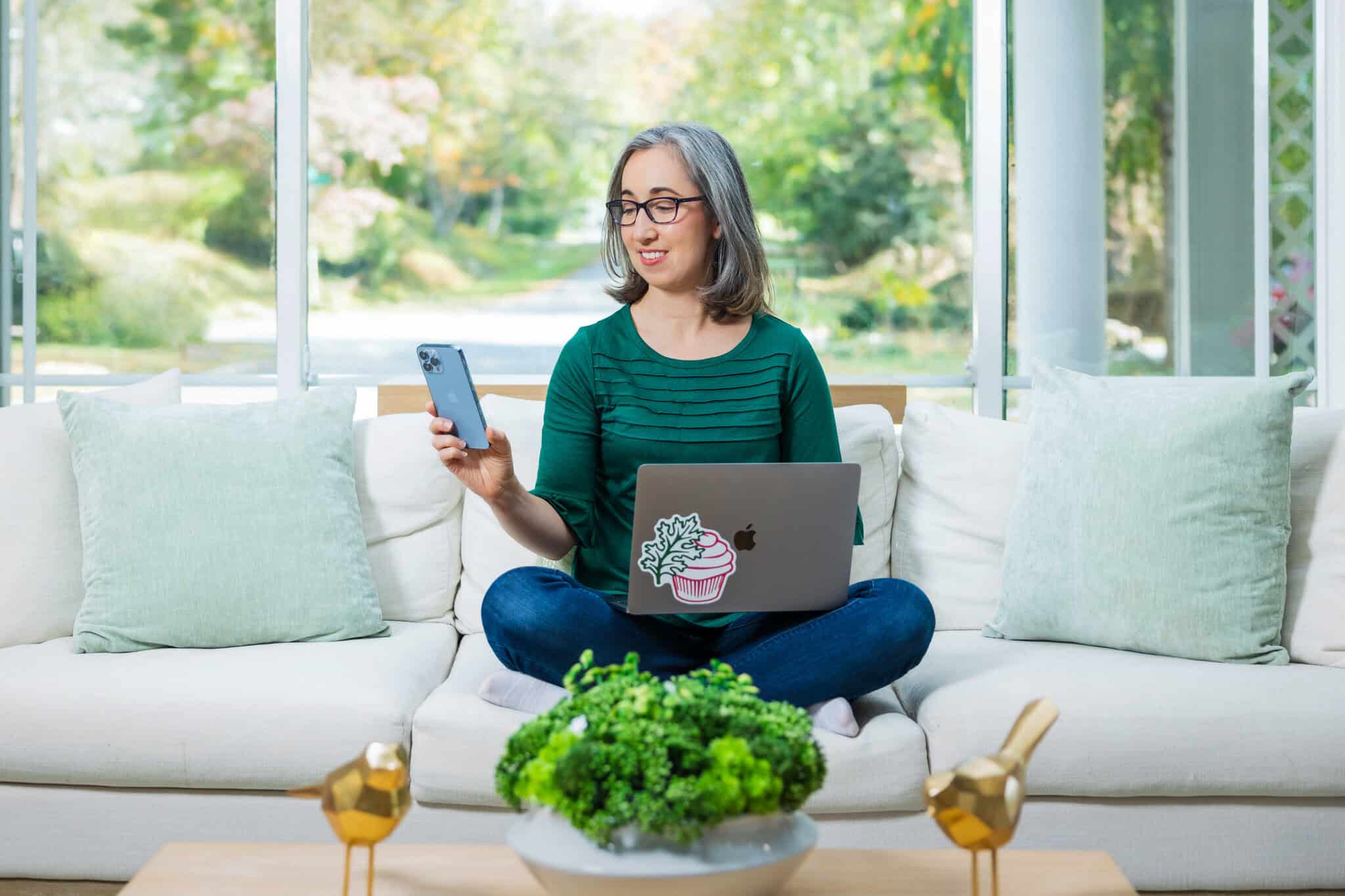 Brianne Izzo sitting on sofa with laptop working on gluten-free recipe blog.