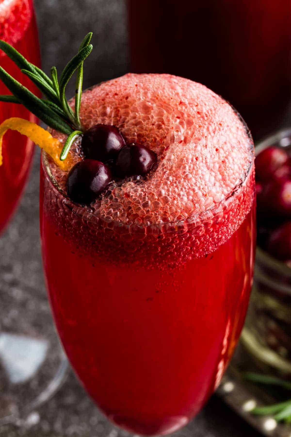 A closeup of a red-colored fizzy mocktail in a flute.