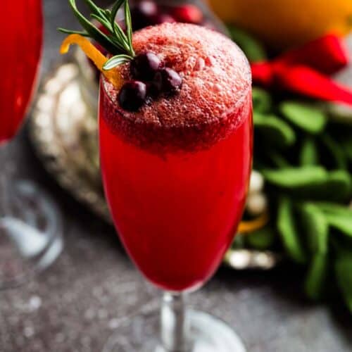 A red-colored fizzy cranberry mocktail in a champagne flute.