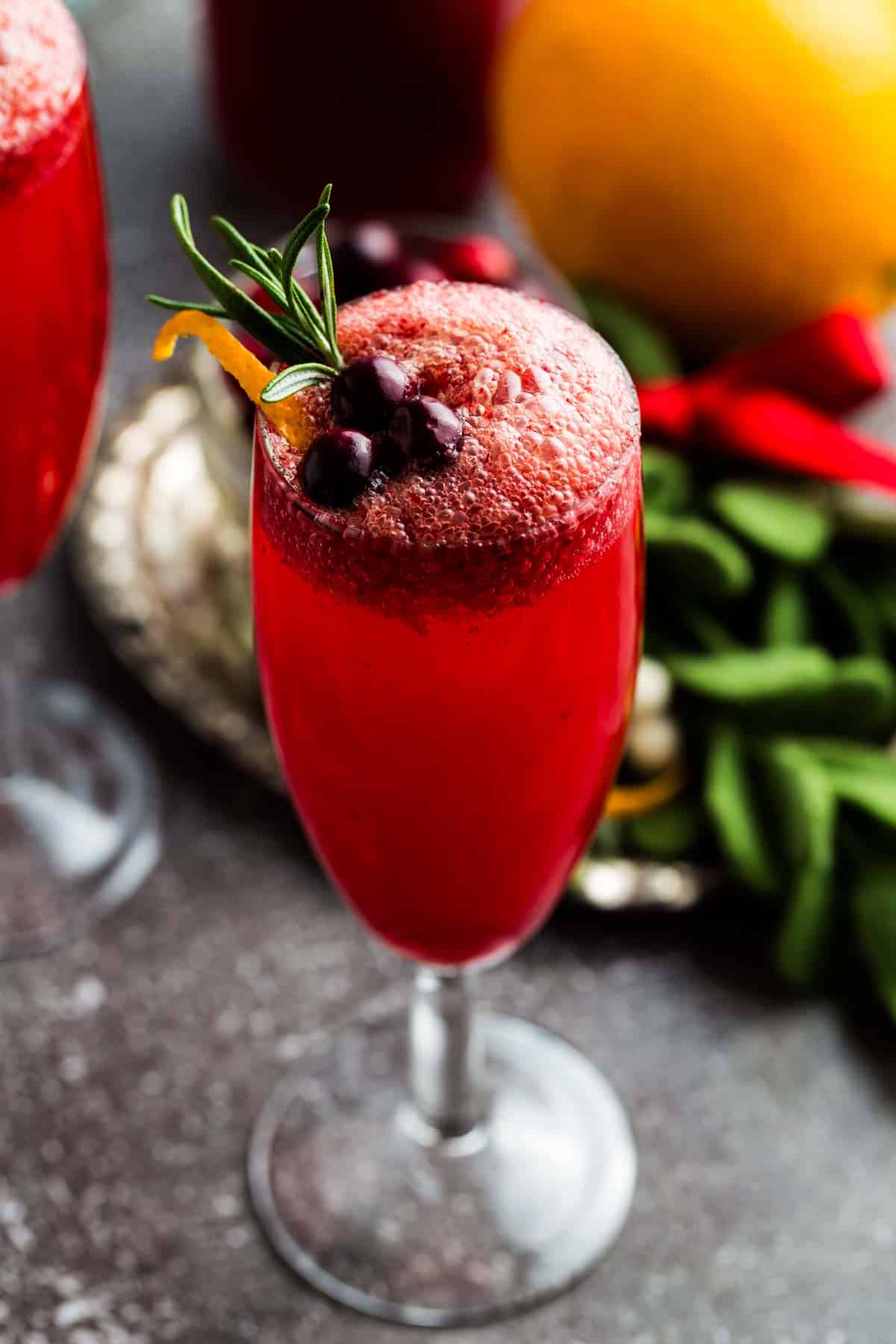 A red-colored fizzy cranberry mocktail in a champagne flute.