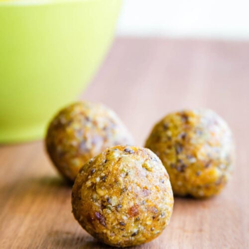 Three apricot energy bites on a wooden board.