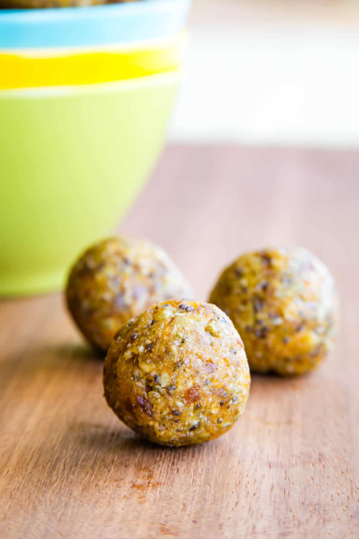 Three apricot energy bites on a wooden board.