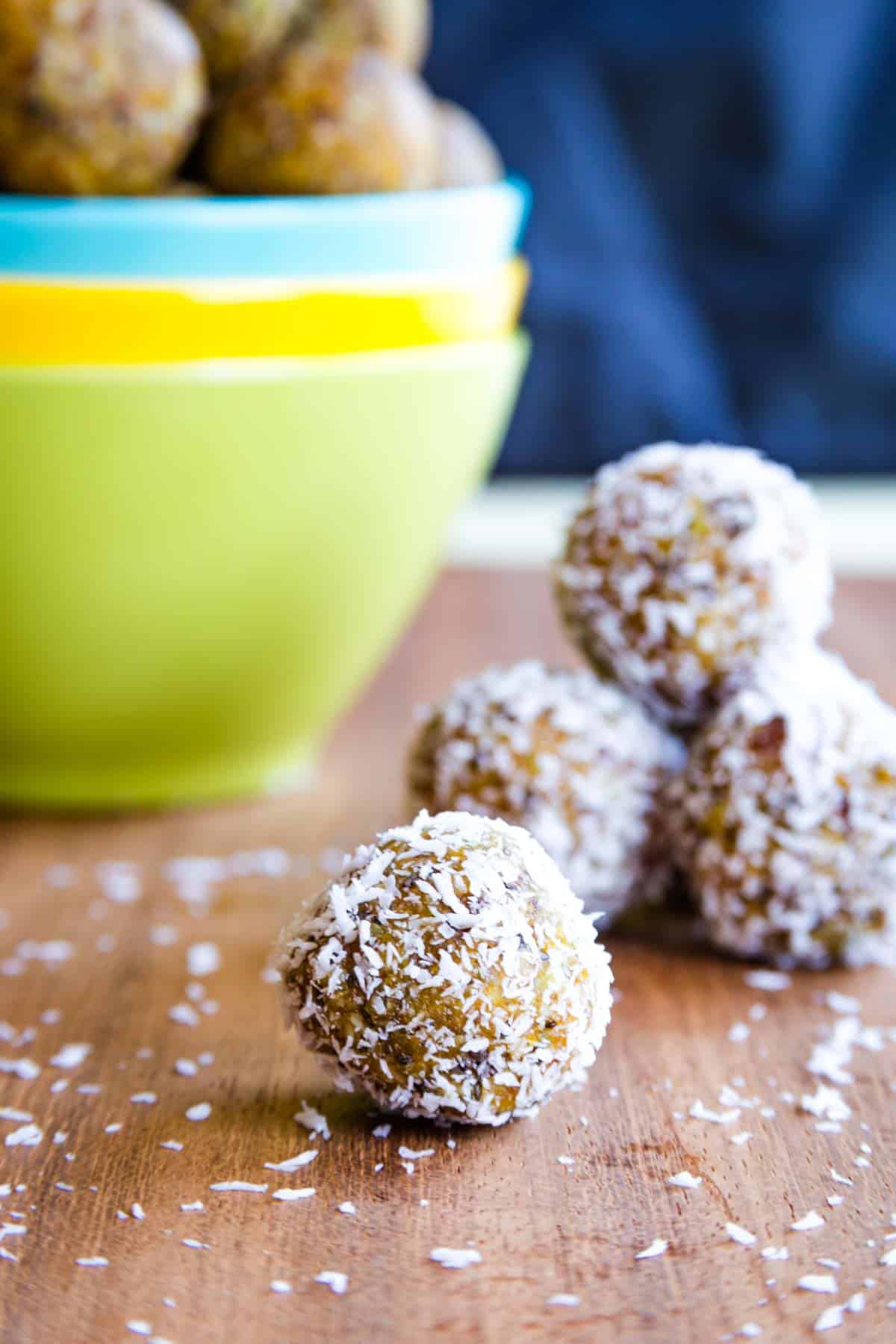 An energy bite that has been coated in coconut with more in the background.