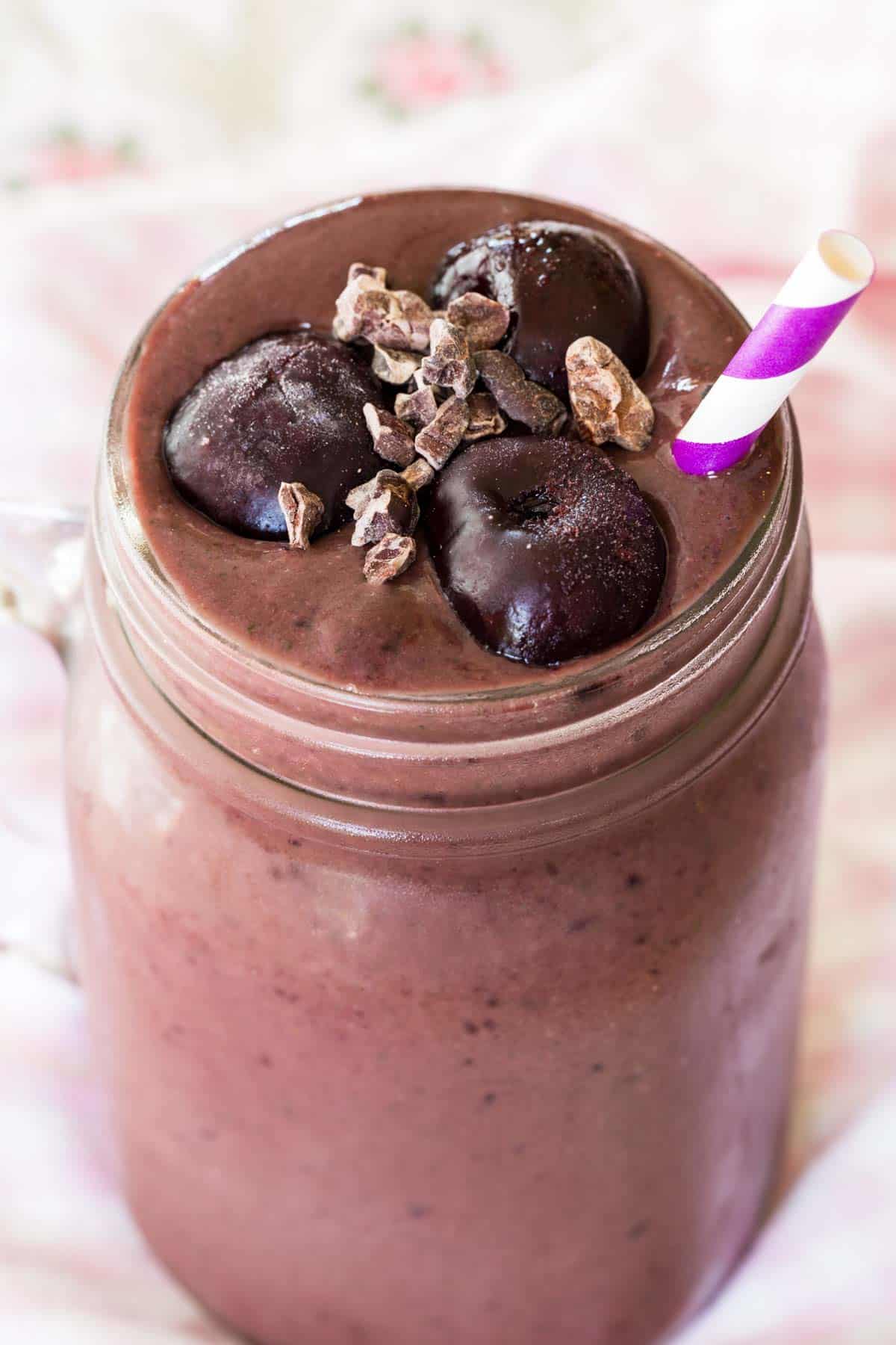 A closeup of the frozen cherries and cacao nibs floating on top of a smoothie.
