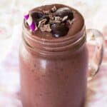 A glass jar filled to the top with a cherry smoothie.