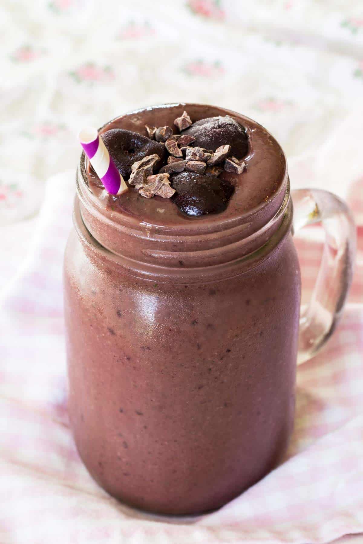 A glass jar filled to the top with a cherry smoothie.