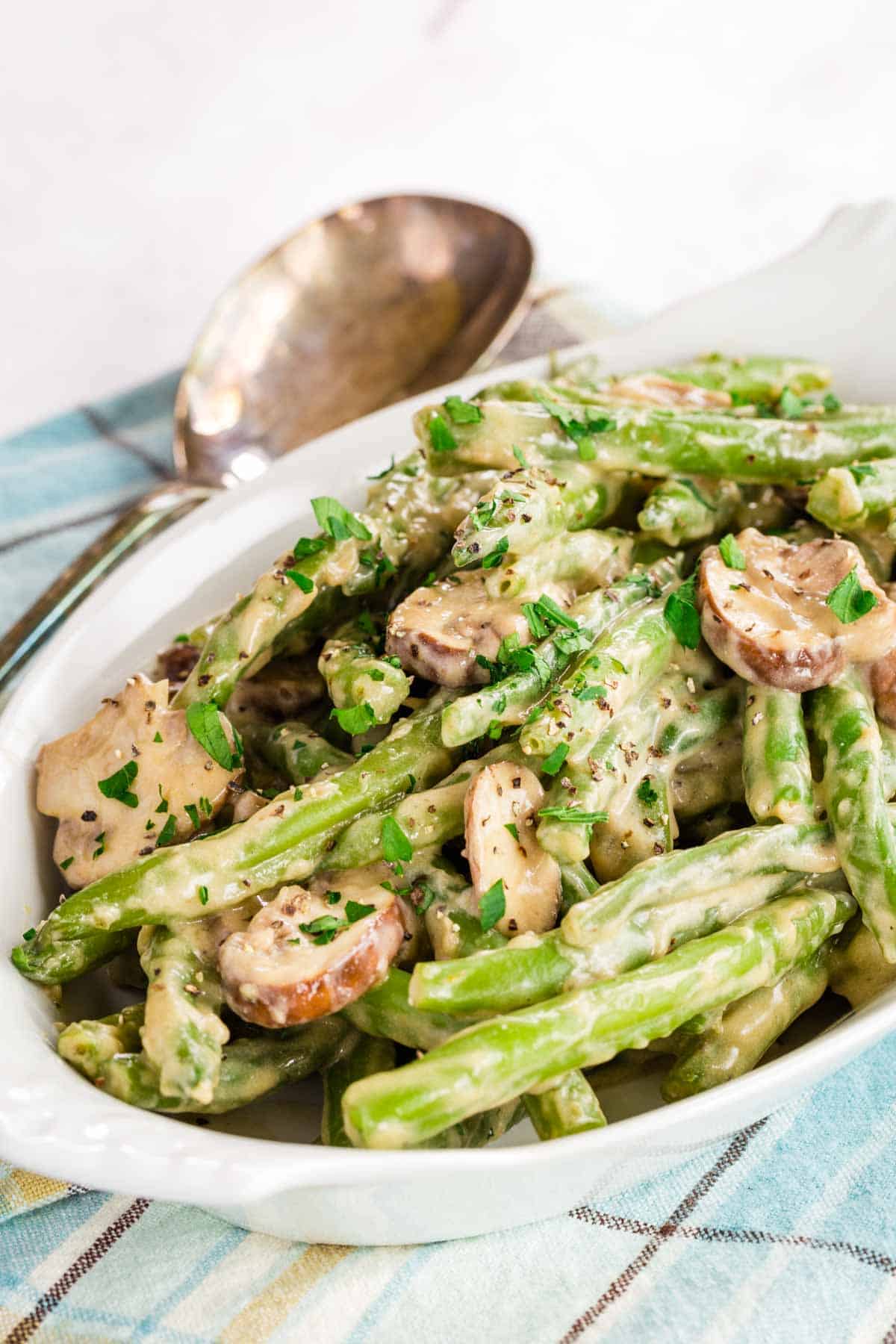 A dish of creamy green beans and mushrooms garnished with parsley.