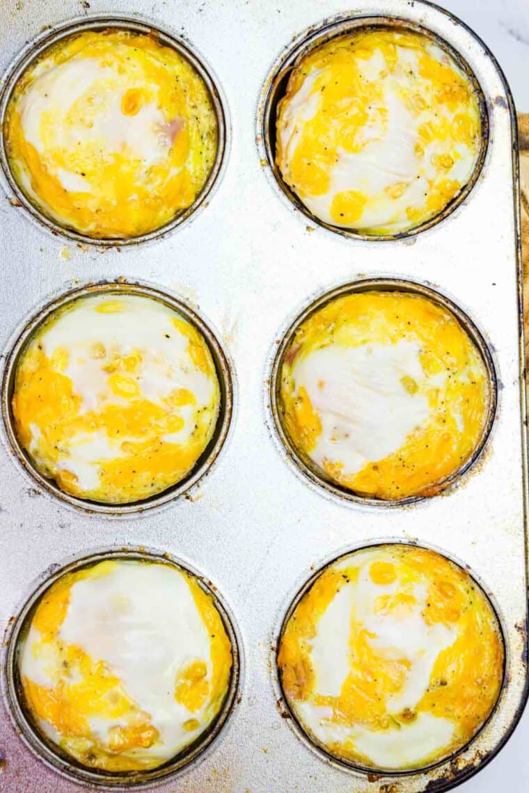 A closeup of the tops of six of the baked egg muffins in the pan.