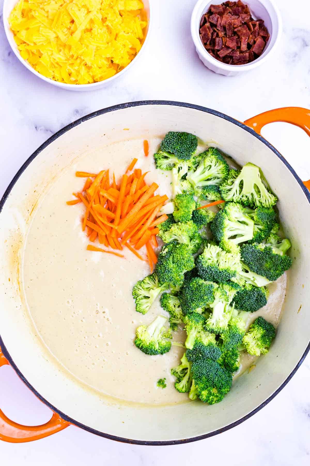 Broccoli florets and julienned carrots added to the cauliflower puree in a pot.