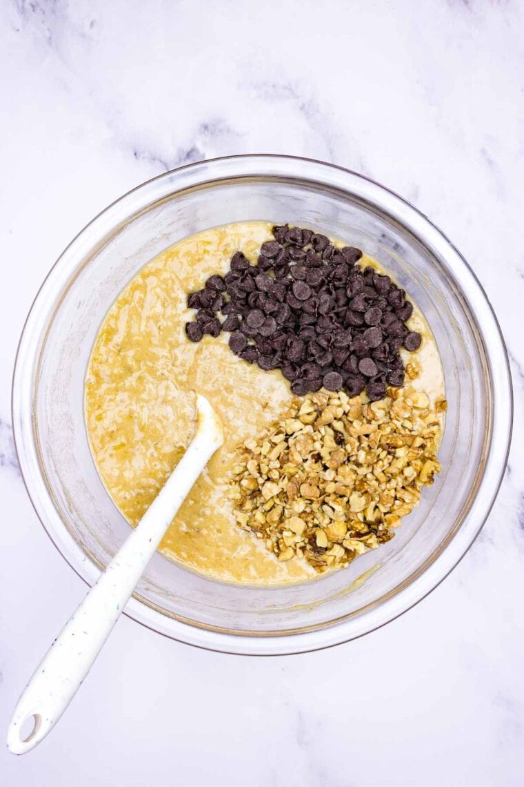 Adding chocolate chips and walnuts to banana bread batter