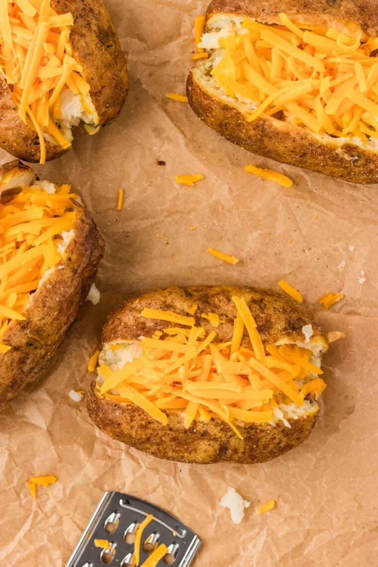 Overhead view of baked potatoes with cheddar cheese on top