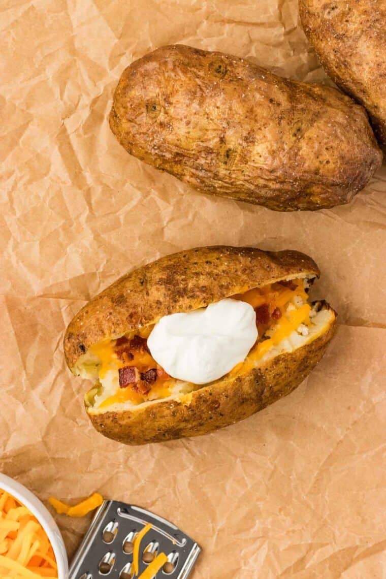 Sour cream on top of bacon and cheese in a baked potato