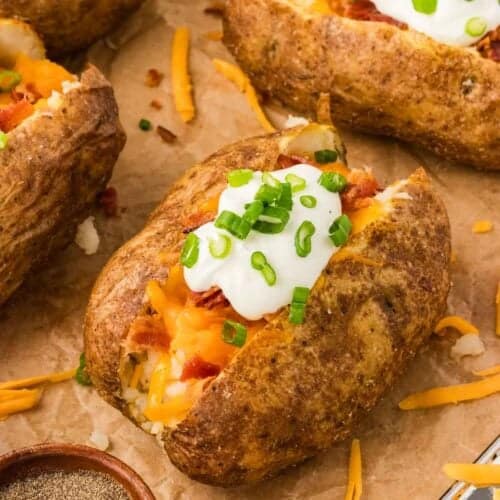 A loaded baked potato on parchment paper
