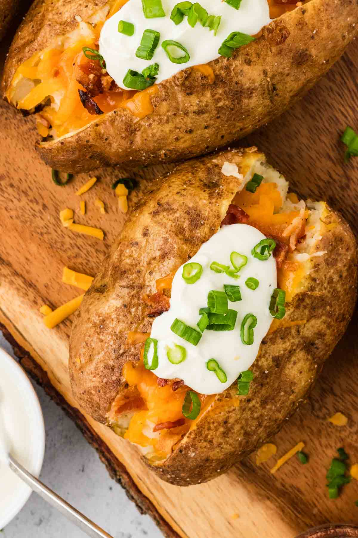 Overhead view of a loaded baked potato on a cutting board