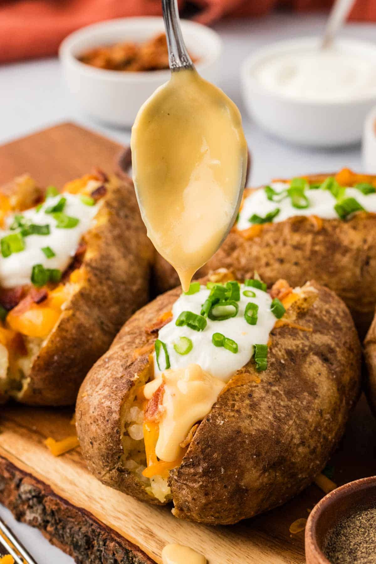 Drizzling cheese sauce over a loaded baked potato