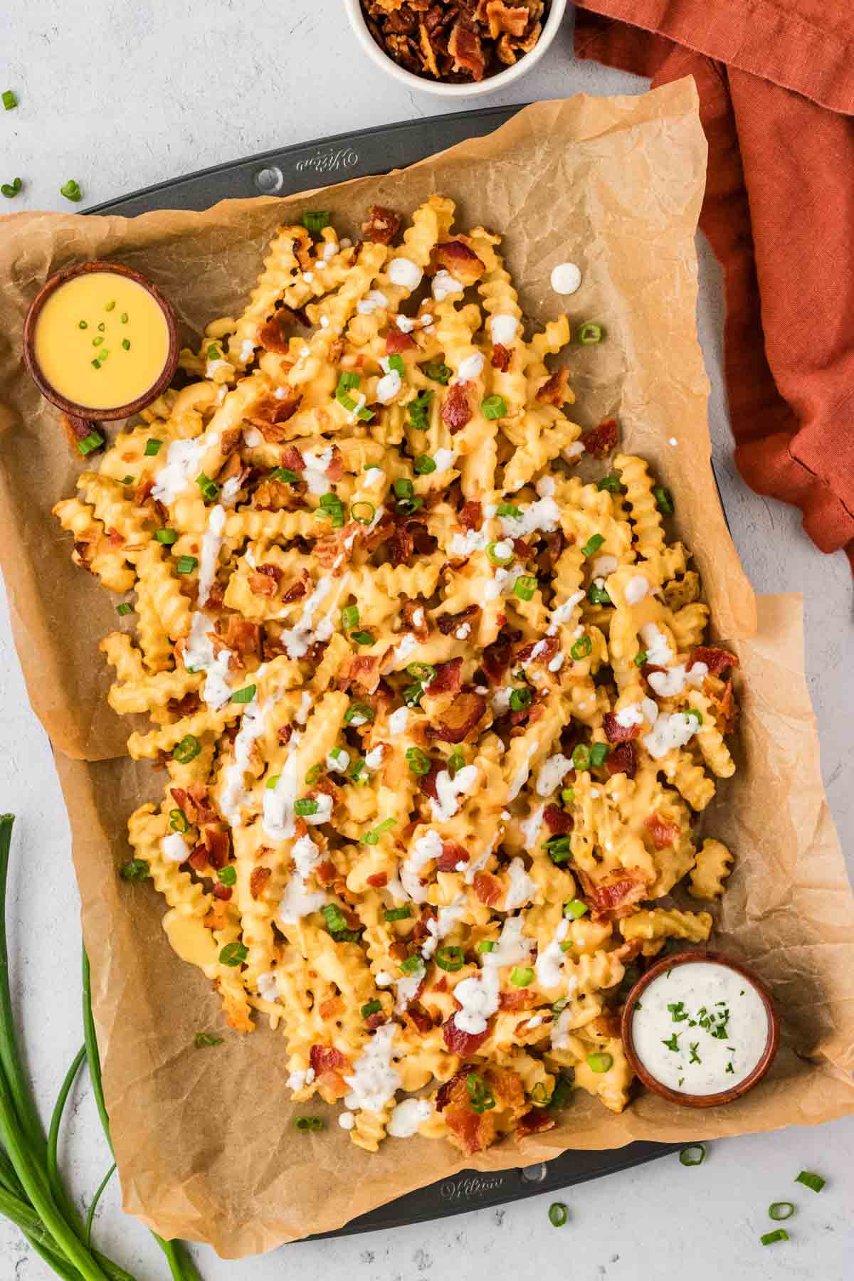Overhead view of loaded french fries with containers of ranch and cheese sauce