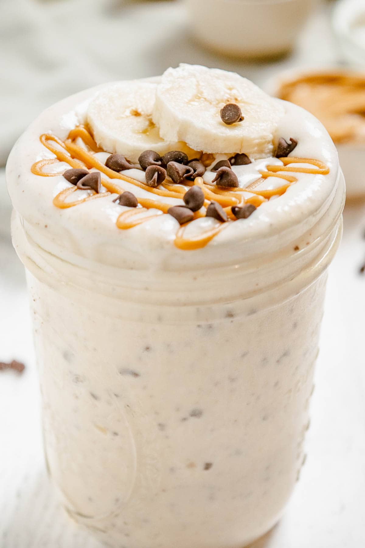 A closeup of a peanut butter banana smoothie in a glass jar.