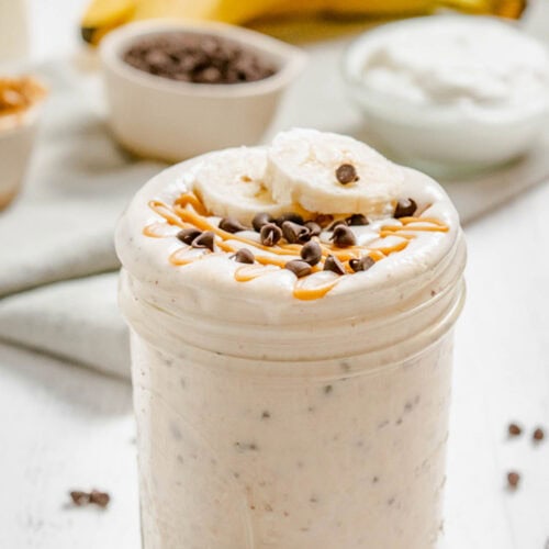 A peanut butter banana smoothie in a jar with mini chocolate chips blended into it.