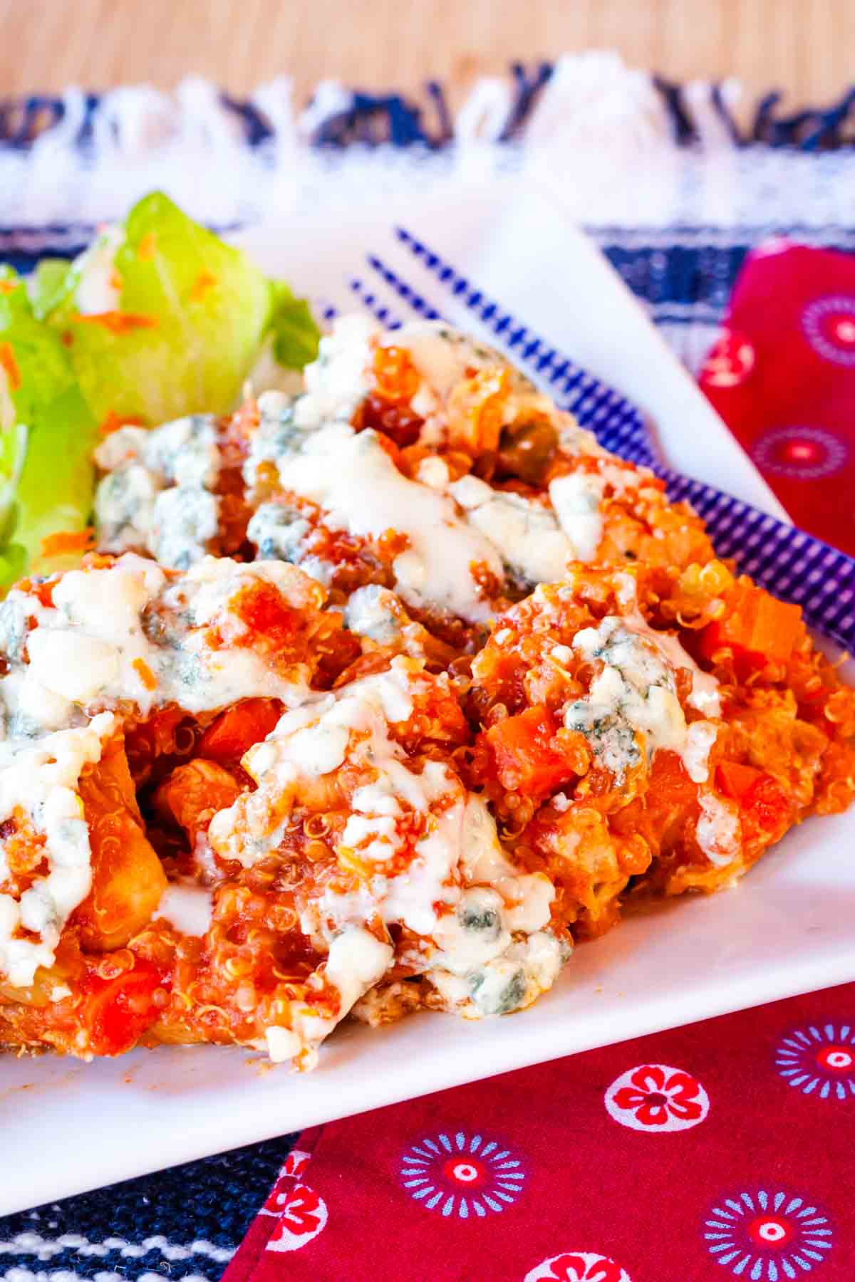 A close-up of the Buffalo chicken quinoa topped with blue cheese crumbles and a drizzle of ranch dressing.