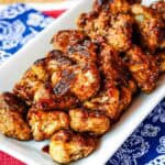 Cauliflower florets coated in a sticky glaze on a white platter.