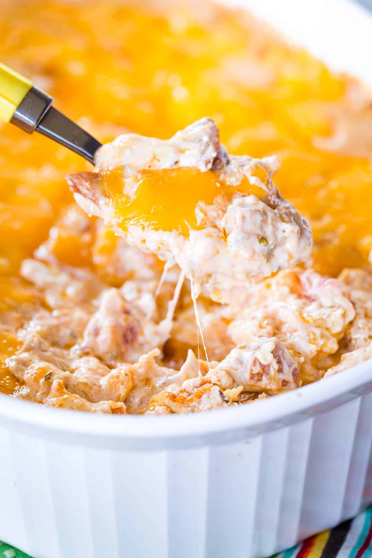 Cheesy Hot Shrimp Jambalaya Dip - the classic New Orleans recipe is transformed into a perfect game day snack or Mardi Gras party appetizer. The perfect warm dip for chips or veggies! Low carb and gluten free. #appetizer #jambalaya #mardigras #glutenfree Some of the cheesy dip being scooped up out of the baking dish with a spoon.