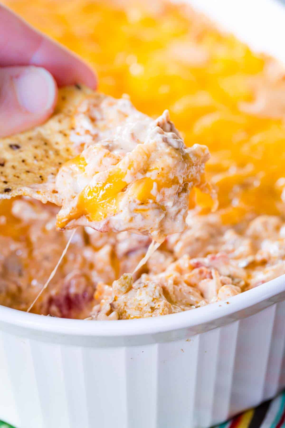 A tortilla chip being used to scoop up hot jambalaya dip.