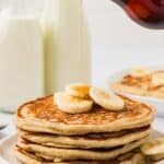 Syrup held over a plate of gluten free banana pancakes