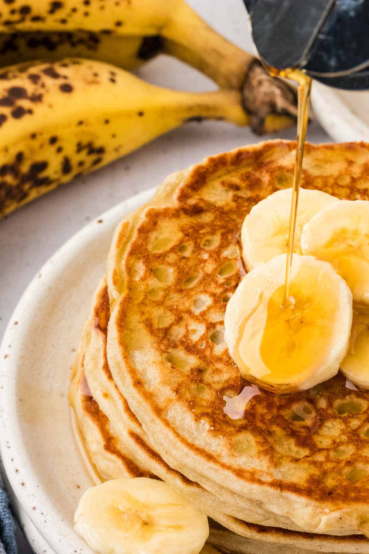 Syrup drizzled onto banana slices over banana pancakes