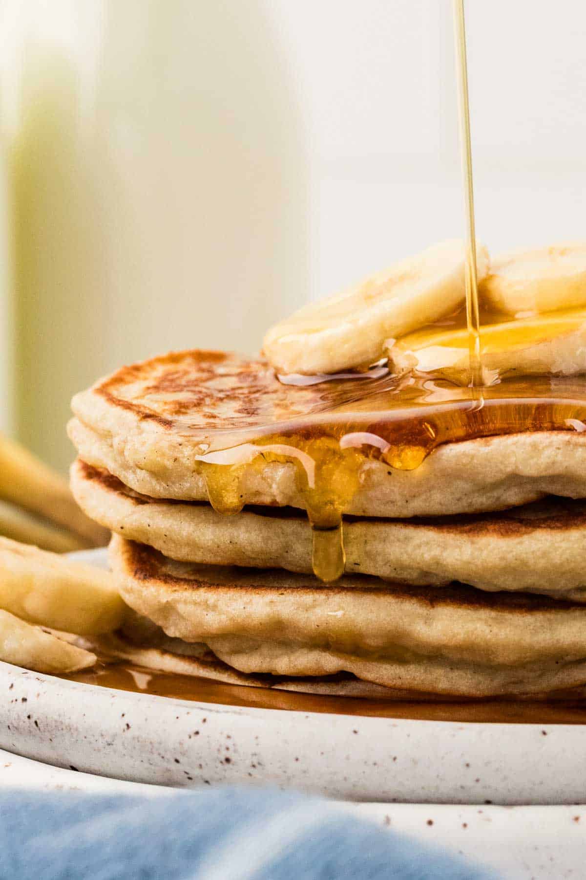 Syrup drizzled on banana slices over banana pancakes