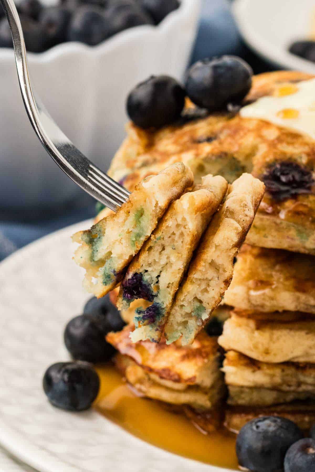 A bite of gluten free blueberry pancakes on a fork