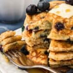 A fork laying next to a stack of gluten free blueberry pancakes