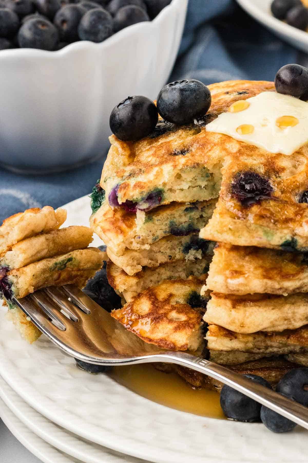 A fork laying next to a stack of gluten free blueberry pancakes
