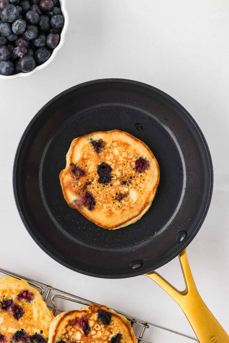 A cooked blueberry pancake in a skillet