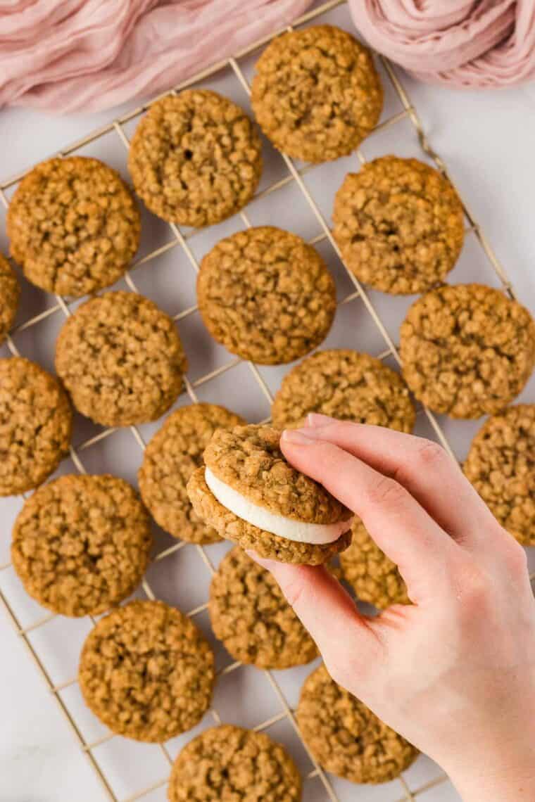 A hand pressing together an oatmeal cream pie sandwich cookie
