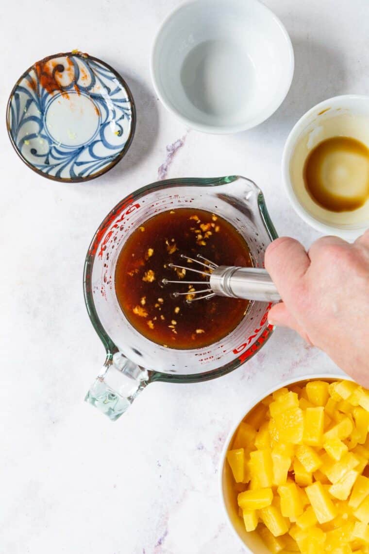 Sauce ingredients being whisked in a glass measuring cup.