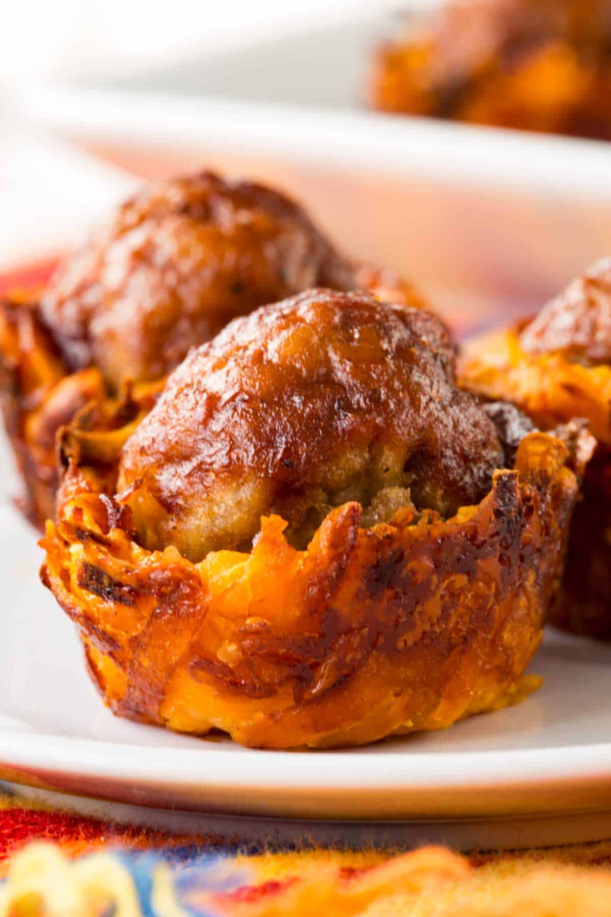 A closeup of one sweet potato cup topped with a meatball.