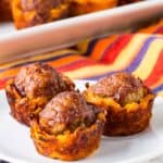 Three small sweet potato cups each topped with a meatball on a small white plate.