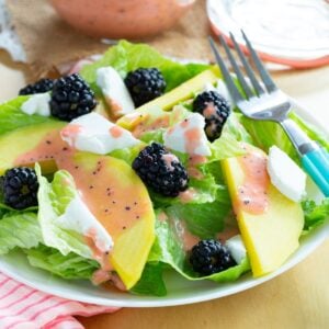 A mango blackberry goat cheese salad on a plate with a fork.